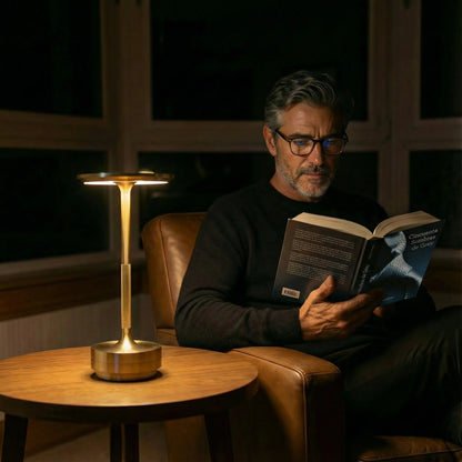 Lámpara de mesa inalámbrica recargable Eclara Ilumina dorada iluminando momento de lectura en salón premium
