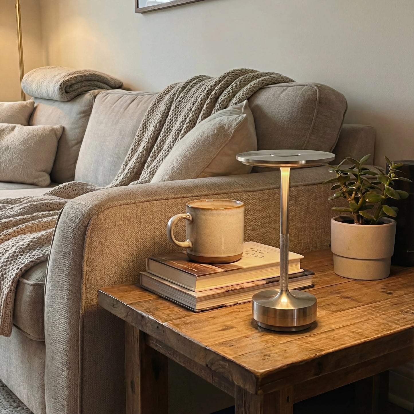 Lámpara de mesa recargable Eclara Ilumina dorada sobre mesa de madera en salón con sofá beige taza ocre y libros decoración hogar
