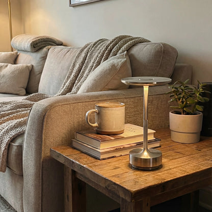 Lámpara de mesa recargable Eclara Ilumina dorada sobre mesa de madera en salón con sofá beige taza ocre y libros decoración hogar